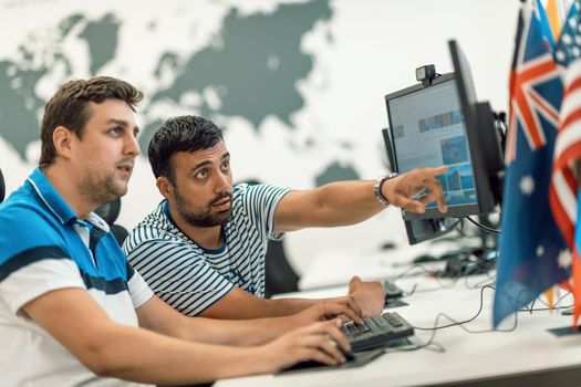 Group of Casual businessmen working on a desktop computer in modern open plan startup office interior. Selective focus. High-quality photo