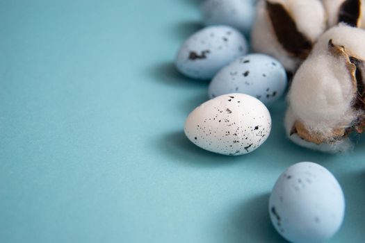 Easter background. Blue and white painted quail eggs on a blue background, decorated with cotton. Happy Easter holiday.