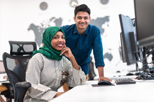 Multiethnic startup business team Arabian woman wearing a hijab on meeting in modern open plan office interior brainstorming, working on laptop and desktop computer. Selective focus. High-quality photo