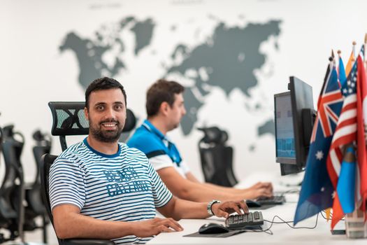 Group of Casual businessmen working on a desktop computer in modern open plan startup office interior. Selective focus. High-quality photo