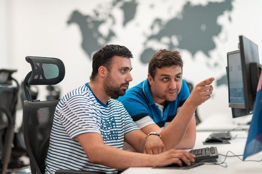 Group of Casual businessmen working on a desktop computer in modern open plan startup office interior. Selective focus. High-quality photo