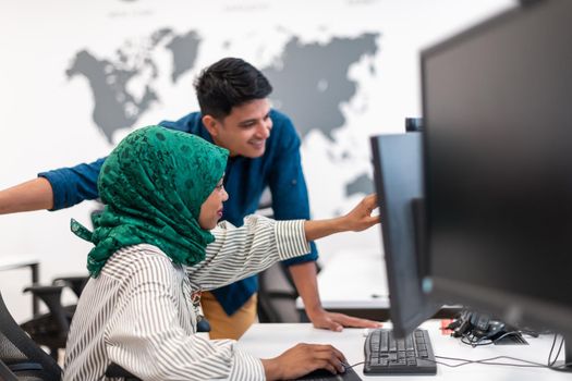 Multiethnic startup business team Arabian woman wearing a hijab on meeting in modern open plan office interior brainstorming, working on laptop and desktop computer. Selective focus. High-quality photo