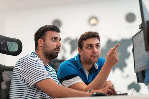 Group of Casual businessmen working on a desktop computer in modern open plan startup office interior. Selective focus. High-quality photo