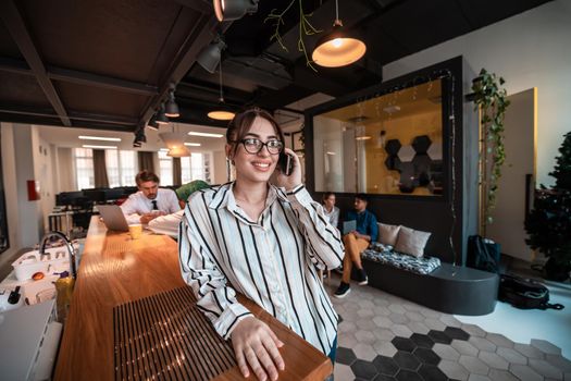 Businesswoman with glasses using a smartphone at modern startup open plan office interior. Selective focus. High-quality photo