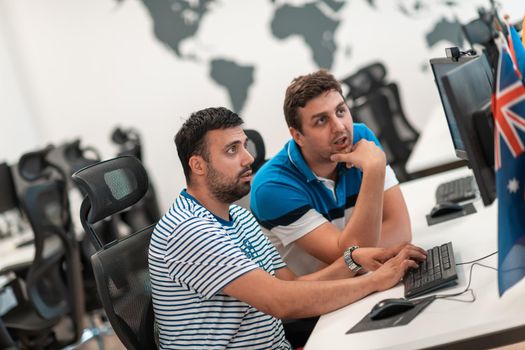 Group of Casual businessmen working on a desktop computer in modern open plan startup office interior. Selective focus. High-quality photo