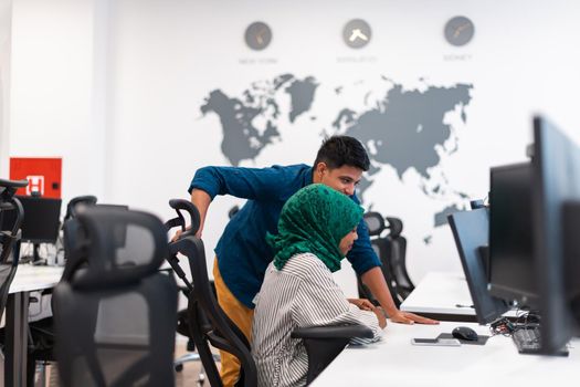 Multiethnic startup business team Arabian woman wearing a hijab on meeting in modern open plan office interior brainstorming, working on laptop and desktop computer. Selective focus. High-quality photo