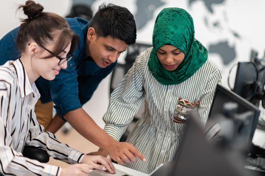 Multiethnic startup business team Arabian woman wearing a hijab on meeting in modern open plan office interior brainstorming, working on laptop and desktop computer. Selective focus. High-quality photo