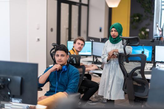 Multiethnic startup business team Arabian woman wearing a hijab on meeting in modern open plan office interior brainstorming, working on laptop and desktop computer. Selective focus. High-quality photo