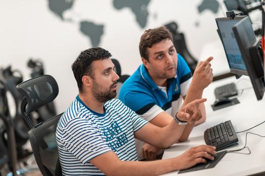 Group of Casual businessmen working on a desktop computer in modern open plan startup office interior. Selective focus. High-quality photo