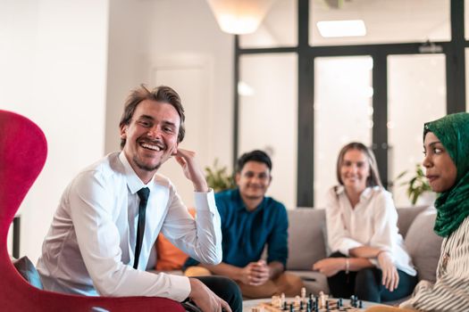 Multiethnic group of businesspeople playing chess while having a break in relaxation area at modern startup office. High-quality photo