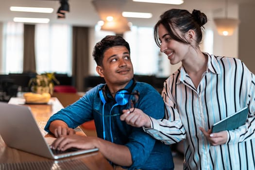 Multiethnic business people man with a female colleague working together on tablet and laptop computer in relaxation area of modern startup office. High-quality photo