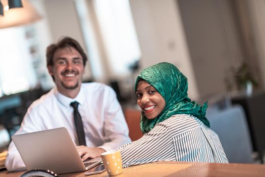 International multicultural business team.Man and Muslim woman with hijab working together using smartphone and laptop location area at modern open plan startup office puter in real. High-quality photo