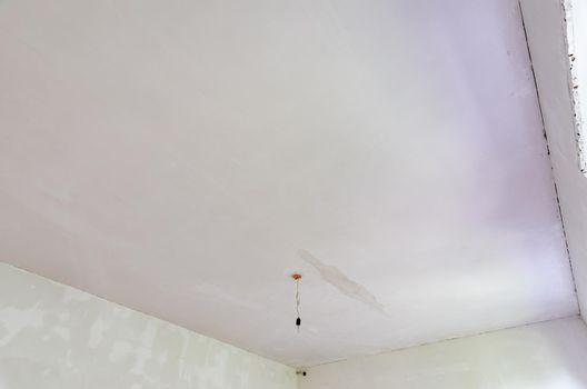 Plastered ceiling in the room, stains from flooding from above are visible on the ceiling a