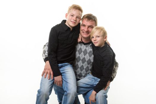 Half-length portrait of a father and two sons in casual clothes on a white background a