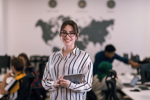 Portrait of businesswoman in casual clothes holding tablet computer at modern startup open plan office interior. Selective focus. High-quality photo