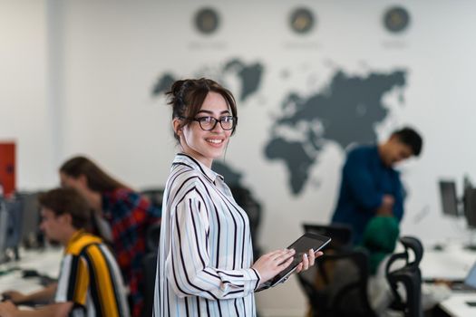 Portrait of businesswoman in casual clothes holding tablet computer at modern startup open plan office interior. Selective focus. High-quality photo