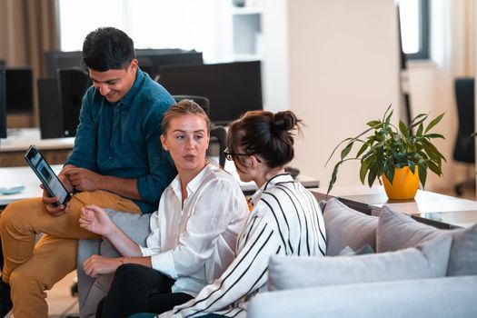 Group of casual multiethnic businesspeople taking a break from the work doing different things while enjoying free time in relaxation area at modern open plan startup office. High-quality photo