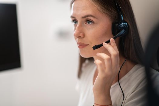 Helpline female operator with headphones in a call center.Business woman with headsets working in a call center. Selective focus. High-quality photo