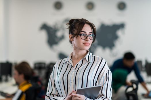 Portrait of businesswoman in casual clothes holding tablet computer at modern startup open plan office interior. Selective focus. High-quality photo