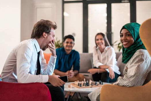 Multiethnic group of businesspeople playing chess while having a break in relaxation area at modern startup office. High-quality photo