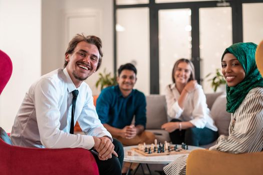 Multiethnic group of businesspeople playing chess while having a break in relaxation area at modern startup office. High-quality photo