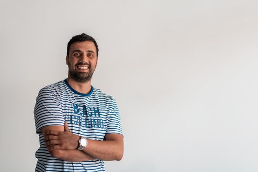 Formal business male portrait. A confident successful casual businessman or manager stands in front of a white background, arms crossed, looking directly at the camera and smiling friendly. High-quality photography.