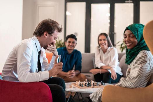 Multiethnic group of businesspeople playing chess while having a break in relaxation area at modern startup office. High-quality photo