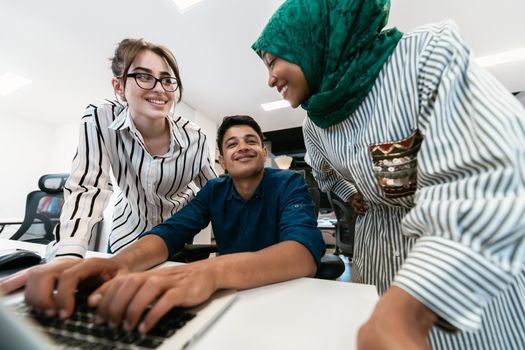 Multiethnic startup business team Arabian woman wearing a hijab on meeting in modern open plan office interior brainstorming, working on laptop and desktop computer. Selective focus. High-quality photo