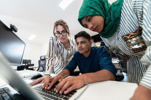 Multiethnic startup business team Arabian woman wearing a hijab on meeting in modern open plan office interior brainstorming, working on laptop and desktop computer. Selective focus. High-quality photo