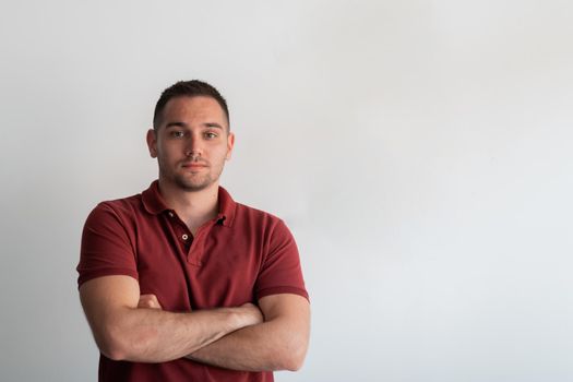 Formal business male portrait. A confident successful casual businessman or manager stands in front of a white background, arms crossed, looking directly at the camera and smiling friendly. High-quality photography.