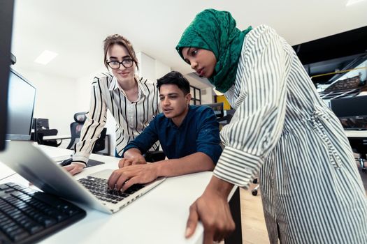 Multiethnic startup business team Arabian woman wearing a hijab on meeting in modern open plan office interior brainstorming, working on laptop and desktop computer. Selective focus. High-quality photo