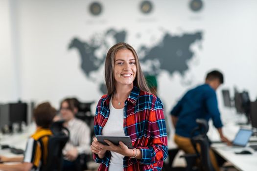 Portrait of businesswoman in casual clothes holding tablet computer at modern startup open plan office interior. Selective focus. High-quality photo