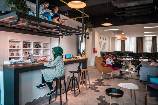 Group of casual multiethnic businesspeople taking a break from the work doing different things while enjoying free time in relaxation area at modern open plan startup office. High-quality photo