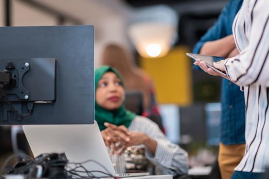 Multiethnic startup business team Arabian woman wearing a hijab on meeting in modern open plan office interior brainstorming, working on laptop and desktop computer. Selective focus. High-quality photo