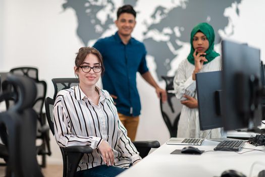 Multiethnic startup business team Arabian woman wearing a hijab on meeting in modern open plan office interior brainstorming, working on laptop and desktop computer. Selective focus. High-quality photo