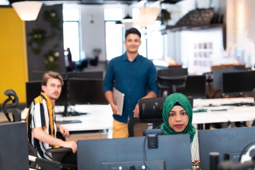 Multiethnic startup business team Arabian woman wearing a hijab on meeting in modern open plan office interior brainstorming, working on laptop and desktop computer. Selective focus. High-quality photo