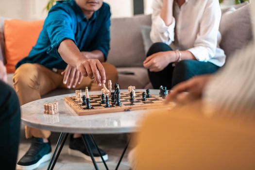 Multiethnic group of businesspeople playing chess while having a break in relaxation area at modern startup office. Selective focus. High-quality photo