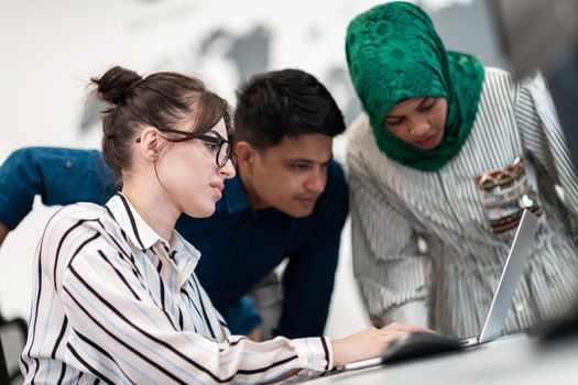 Multiethnic startup business team Arabian woman wearing a hijab on meeting in modern open plan office interior brainstorming, working on laptop and desktop computer. Selective focus. High-quality photo