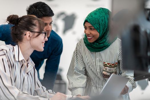 Multiethnic startup business team Arabian woman wearing a hijab on meeting in modern open plan office interior brainstorming, working on laptop and desktop computer. Selective focus. High-quality photo