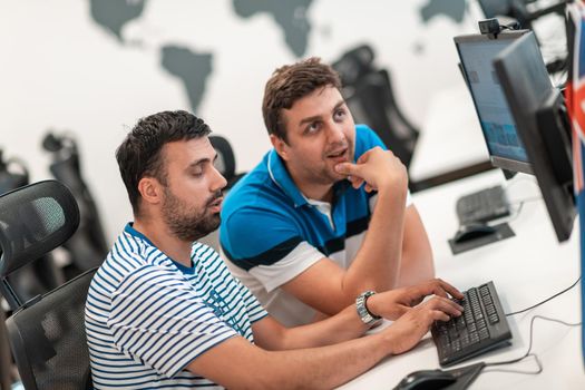 Group of Casual businessmen working on a desktop computer in modern open plan startup office interior. Selective focus. High-quality photo