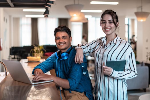 Multiethnic business people man with a female colleague working together on tablet and laptop computer in relaxation area of modern startup office. High-quality photo