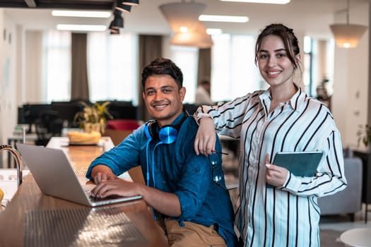 Multiethnic business people man with a female colleague working together on tablet and laptop computer in relaxation area of modern startup office. High-quality photo