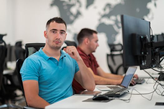 Group of Casual businessmen working on a desktop computer in modern open plan startup office interior. Selective focus. High-quality photo