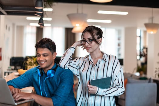 Multiethnic business people man with a female colleague working together on tablet and laptop computer in relaxation area of modern startup office. High-quality photo