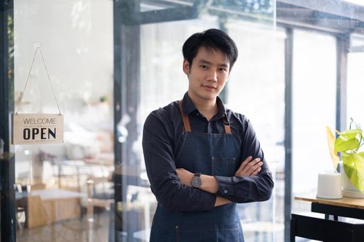 Portrait of Asian Man barista cafe owner smile while cafe open. SME entrepreneur seller business concept