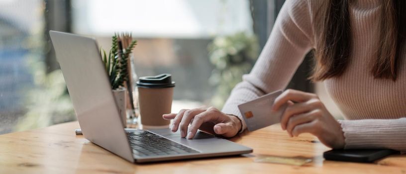 Close up of black girl hold bank credit card and type on laptop, shopping online using computer, buying goods or ordering online, entering bank accounts and details in online banking offer