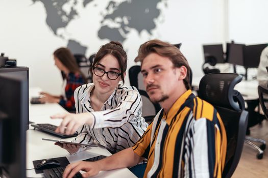 Business couple working together on a project using tablet and desktop computer at modern open plan startup office. Selective focus. High-quality photo