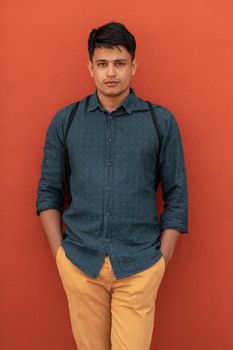 Startup business portrait of casual businessman with a blue shirt and backpack in front of a red wall. High-quality photo