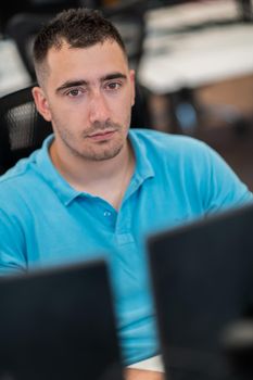 Casual businessman working on a desktop computer in modern open plan startup office interior. Selective focus. High-quality photo