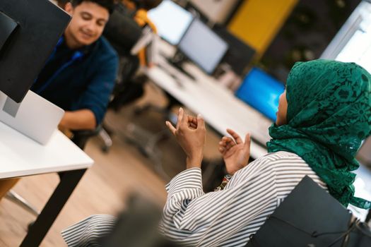 Multiethnic startup business team Arabian woman wearing a hijab on meeting in modern open plan office interior brainstorming, working on laptop and desktop computer. Selective focus. High-quality photo